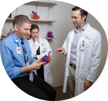 Person holding a fake organ another person points while another laughs