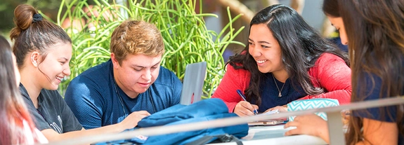 Students working together on a laptop and smiling 