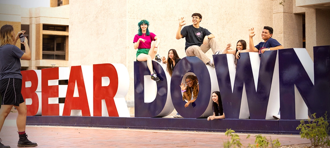 student success district - students taking picture at large bear down sign